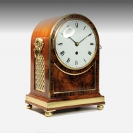 A good table clock in an arched rosewood and brass-bound case. By Thomas Gammage, London. Circa 1835