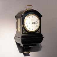 A verge escapement bracket clock on its bracket in an ebonised case and having an enamel dial. Circa